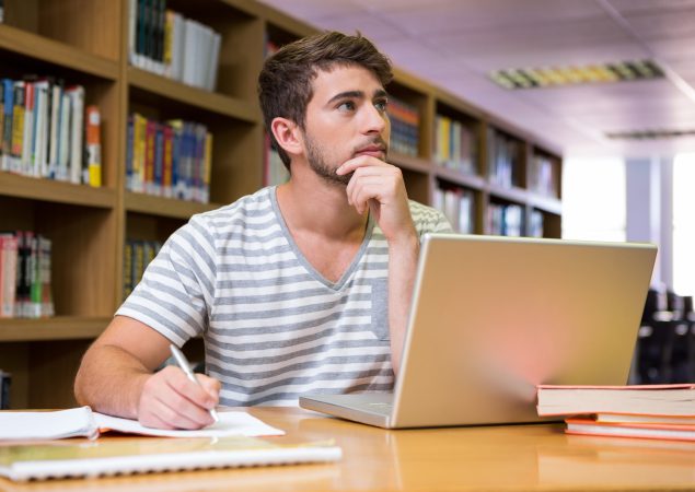 Student studying in the library with laptop at the university
